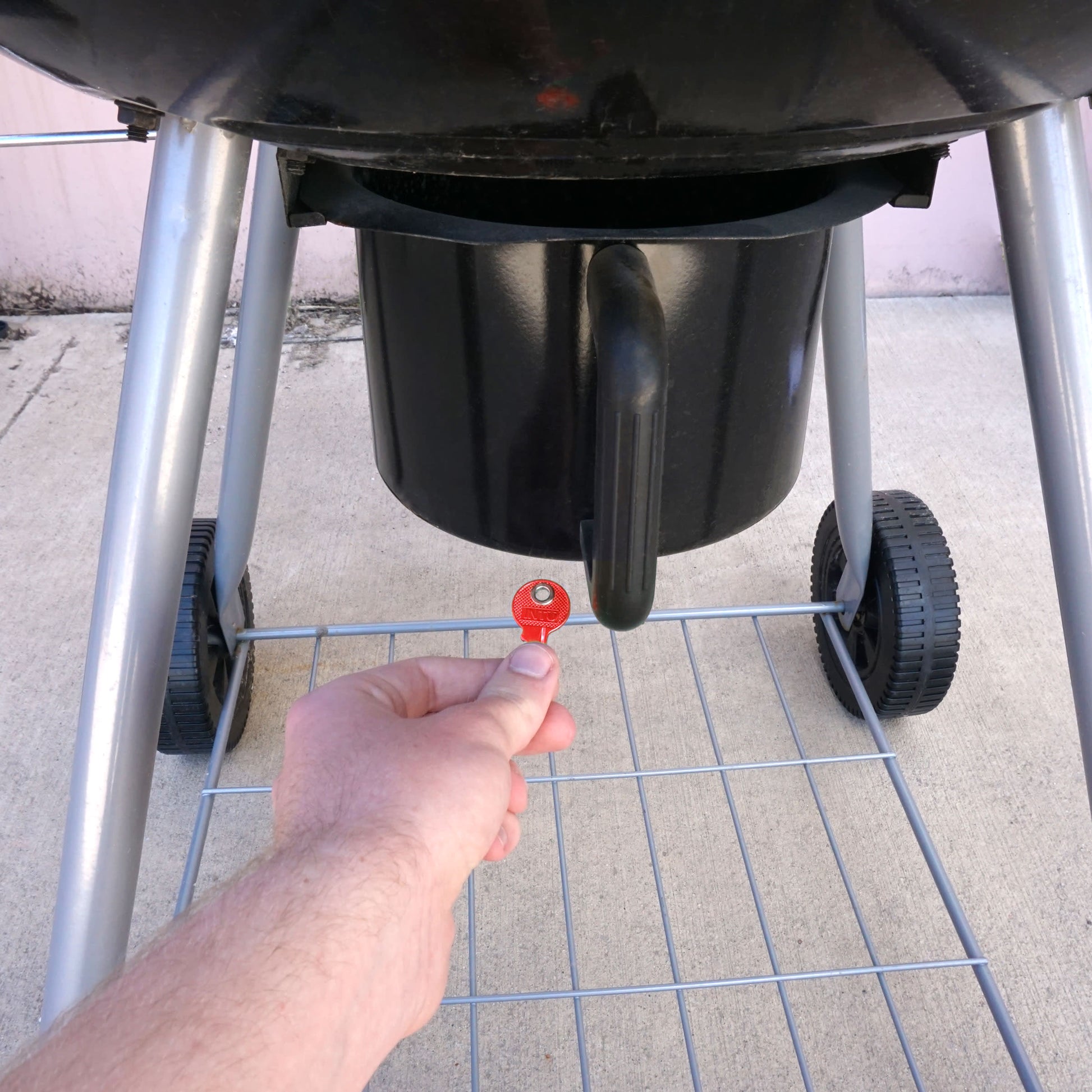 Load image into Gallery viewer, 50692 Magnetic Key, M1-69 Red - Hand Holding Red Magnetic Key Beneath a Barbeque Grill