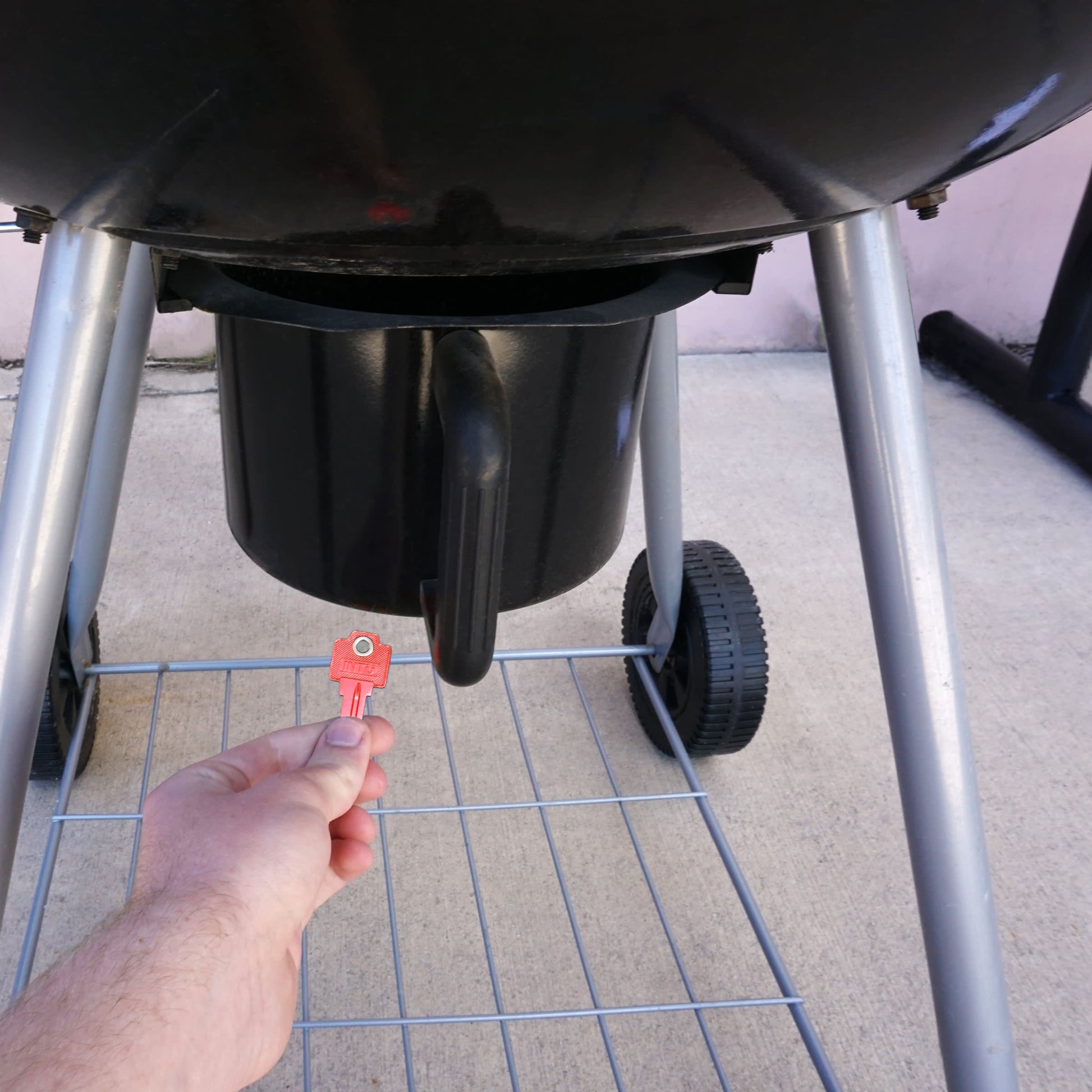 Load image into Gallery viewer, 50772 Magnetic Key, WR5-67 Red - Hand Holding Red Magnetic Key Beneath a Barbeque Grill