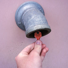 Load image into Gallery viewer, 50662 Magnetic Key, KW1-66 Red - Hand Holding Red Magnetic Key Next to Metal Drain Pipe