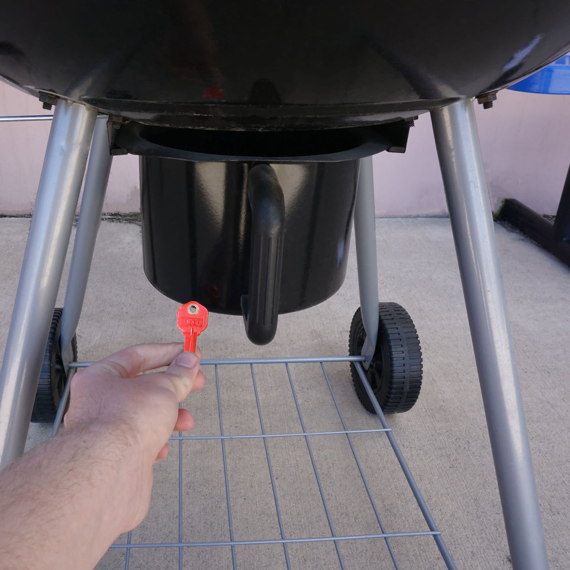 Load image into Gallery viewer, 50662 Magnetic Key, KW1-66 Red - Hand Holding Red Magnetic Key Beneath a Barbeque Grill