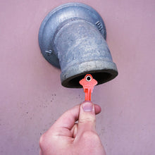 Load image into Gallery viewer, 50682 Magnetic Key, SC1-68 Red - Hand Holding Red Magnetic Key Next to a Drain Pipe