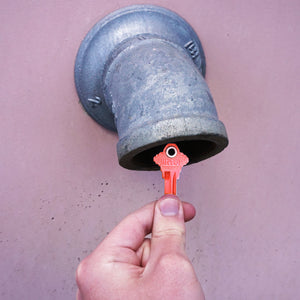 50682 Magnetic Key, SC1-68 Red - Hand Holding Red Magnetic Key Next to a Drain Pipe