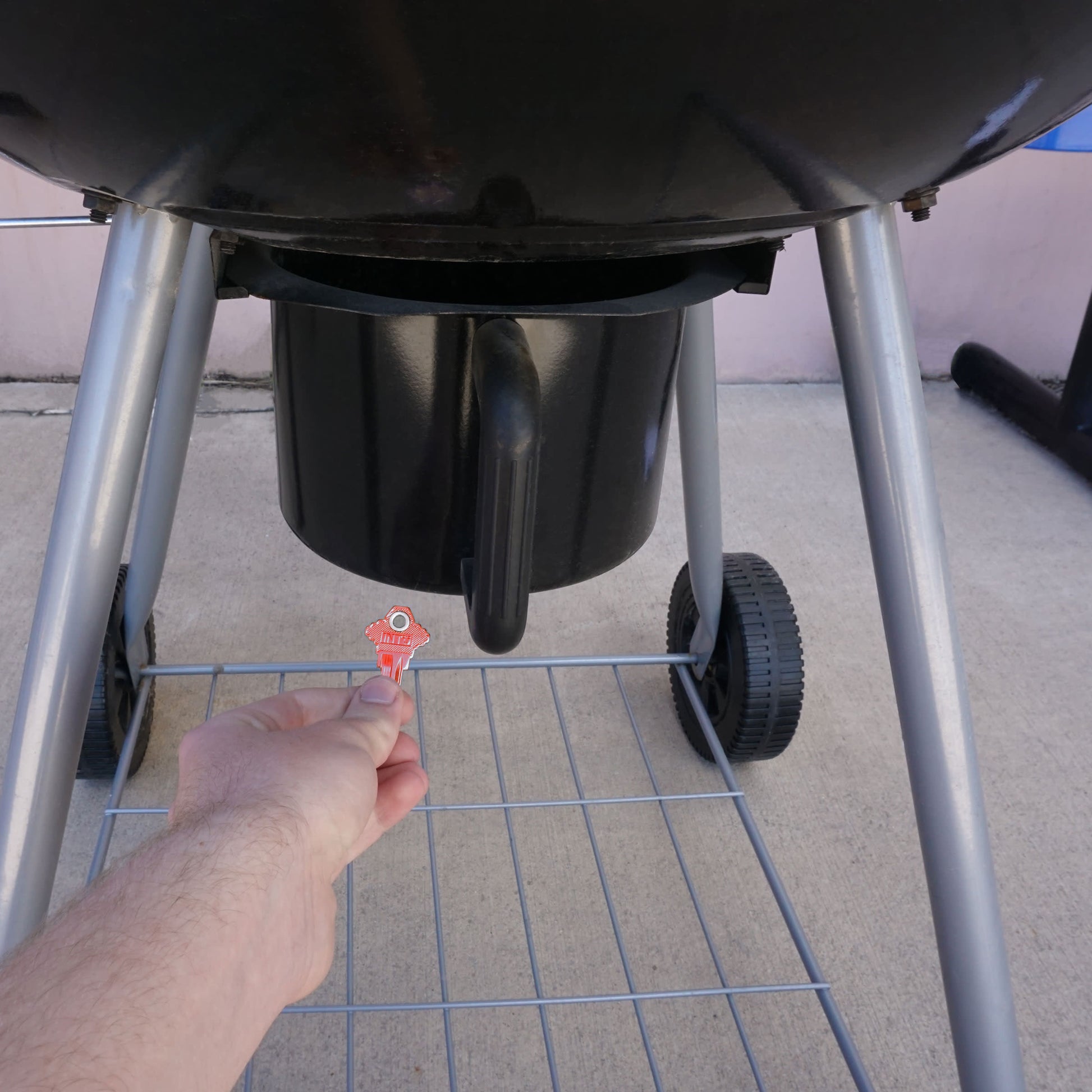 Load image into Gallery viewer, 50682 Magnetic Key, SC1-68 Red - Hand Holding Red Magnetic Key Beneath a Barbeque Grill