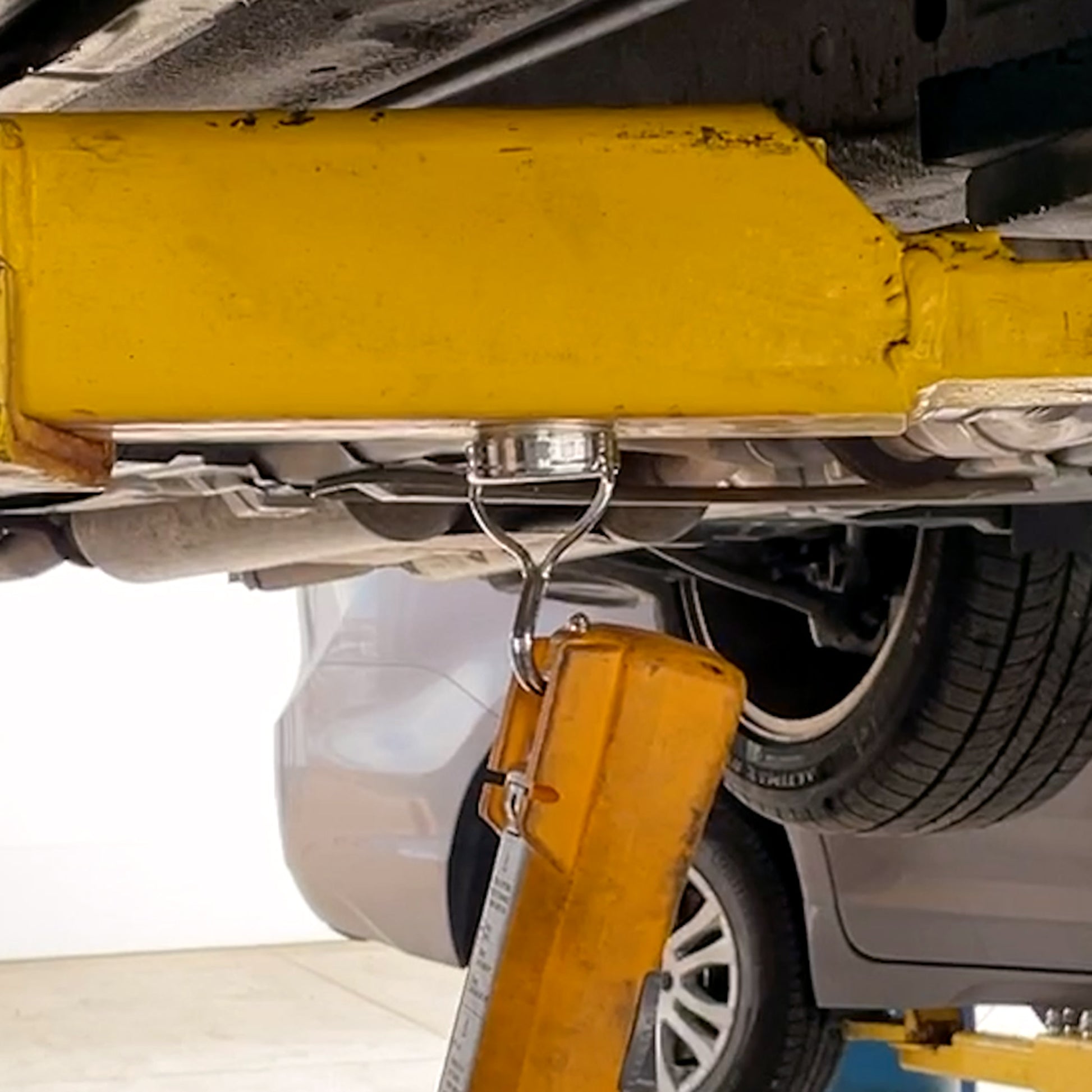 Load image into Gallery viewer, MHHH07548BX Super Blue™ Swinging Magnetic Hook - Demonstration of Hook Attached to Car Lift Holding Heavy Equipment